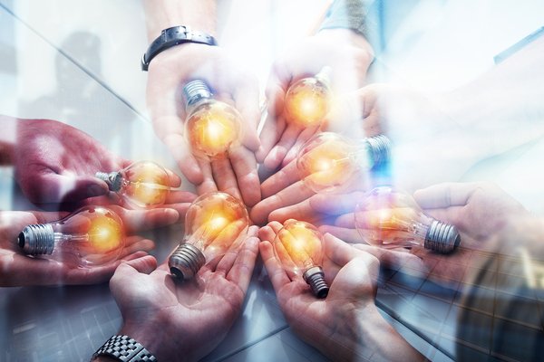 Group of people holding light bulbs in their hands.