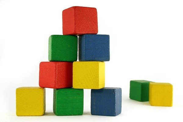 Green, yellow, and blue wood blocks stacked in a pyramid shape.
