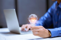 Person holding a lightbulb. Risk-Averse Thinking