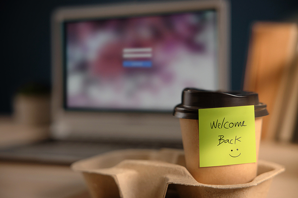 Coffee cup with a sticky note labeled welcome back.